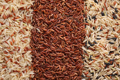 Different types of brown rice as background, top view