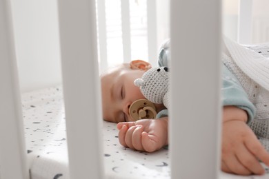 Adorable baby with toy peacefully sleeping in crib