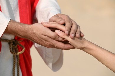 Jesus Christ holding woman's hand in desert, closeup