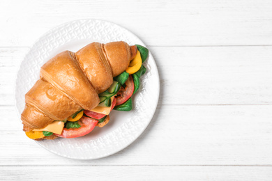 Tasty vegetarian croissant sandwich on white wooden table, top view. Space for text