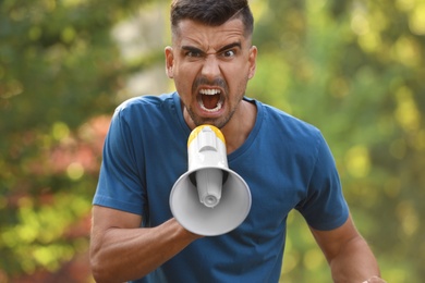 Photo of Angry young man with megaphone outdoors. Protest leader