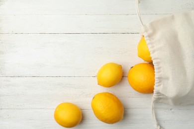 Photo of Cotton eco bag with lemons on white wooden background, flat lay. Space for text