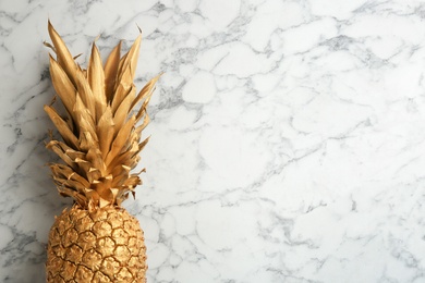 Photo of Golden pineapple on white marble background, top view with space for text. Creative concept