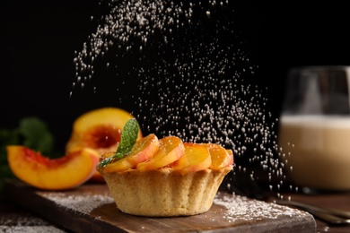 Decorating delicious peach dessert with powdered sugar on wooden board