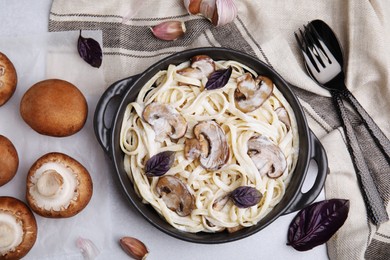 Photo of Delicious pasta with mushrooms served on grey table, flat lay