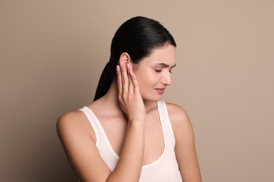Young woman suffering from ear pain on grey background