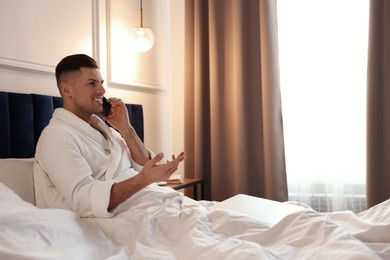 Handsome man talking on phone in hotel room