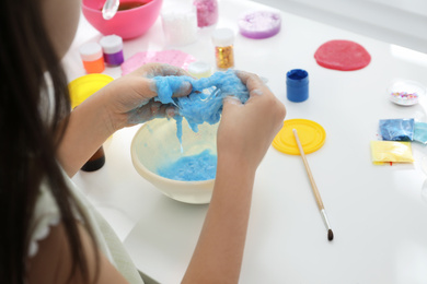 Little girl making DIY slime toy at table, closeup