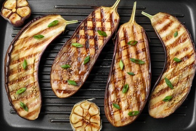 Photo of Delicious grilled eggplant halves in pan, closeup