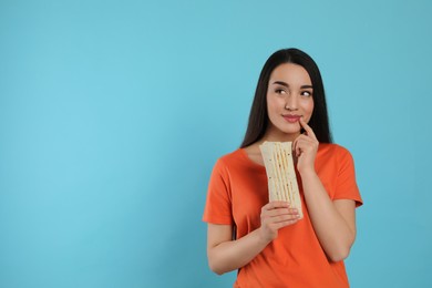 Photo of Dreamy young woman holding tasty shawarma on turquoise background. Space for text