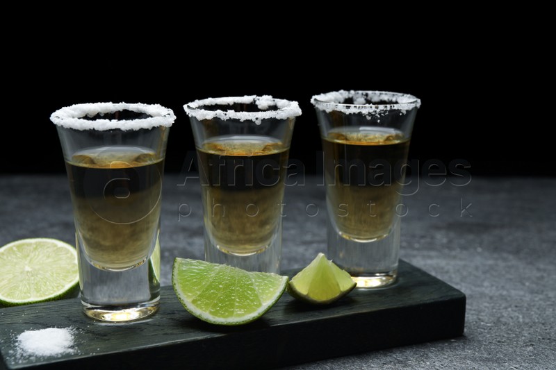 Mexican Tequila shots, lime slices and salt on grey table