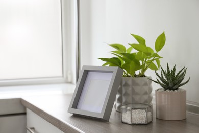 Photo of Beautiful Scindapsus and Aloe in pots with blank photo frame on wooden table, space for text. Different house plants