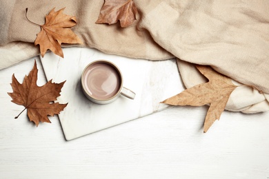 Flat lay composition with hot cozy drink and autumn leaves on wooden background