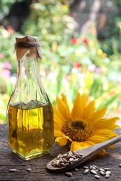 Bottle of sunflower oil and peeled seeds on wooden table outdoors