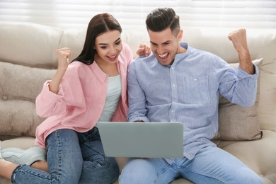 Emotional couple participating in online auction using laptop at home