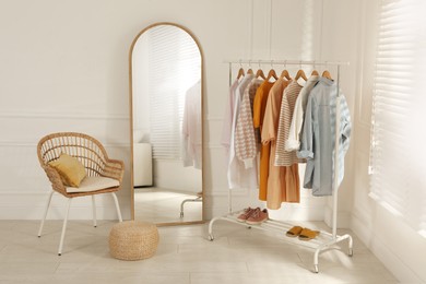 Modern dressing room interior with stylish clothes, shoes and large mirror