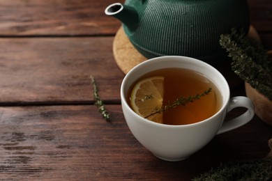 Photo of Aromatic herbal tea with thyme and lemon on wooden table, space for text