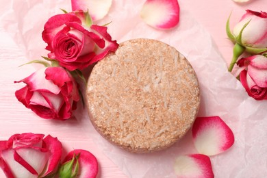 Photo of Solid shampoo bar and roses on pink wooden table, flat lay. Hair care
