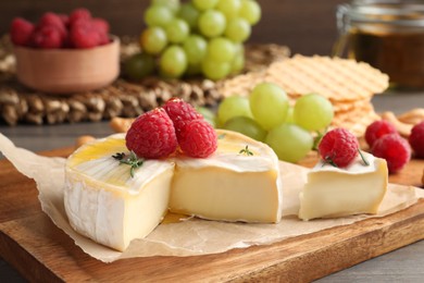 Brie cheese served with berries on table, closeup