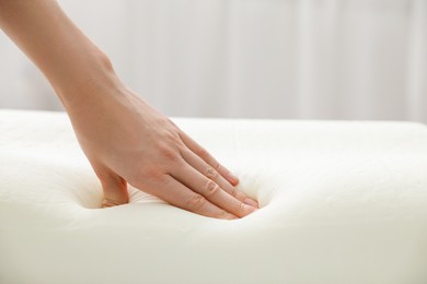 Photo of Woman touching orthopedic memory foam pillow indoors, closeup. Space for text