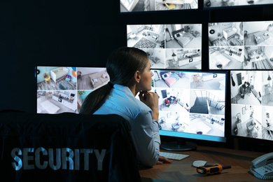 Security guard monitoring modern CCTV cameras indoors at night
