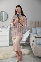 Photo of Young woman taking mirror selfie in stylish outfit at home. Morning routine