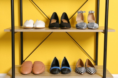 Photo of Different female shoes on shelf unit against color wall