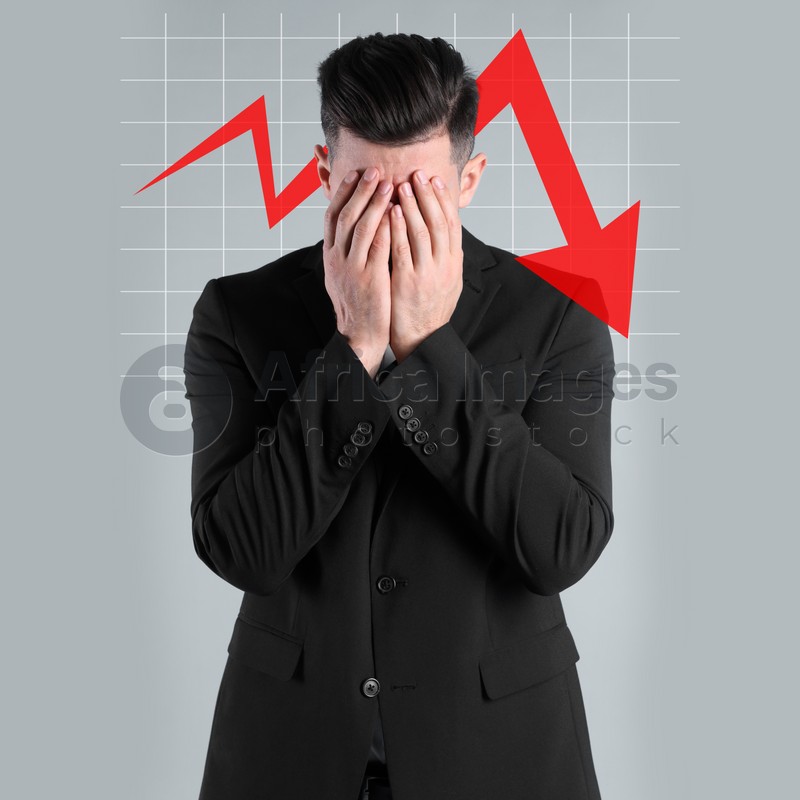 Upset businessman and illustration of falling down chart on light grey background. Economy recession concept