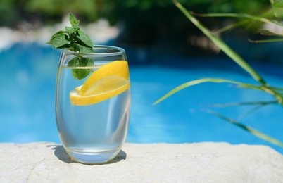 Photo of Refreshing water with lemon and mint on rock outdoors