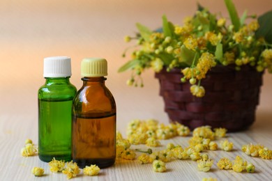 Photo of Bottles of essential oil and linden blossoms on white wooden table