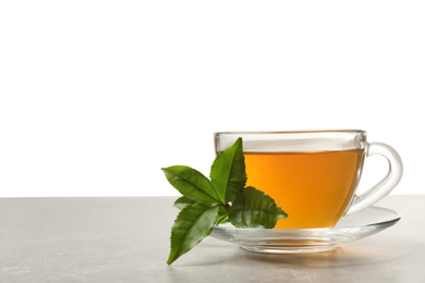 Cup of green tea and leaves on grey table