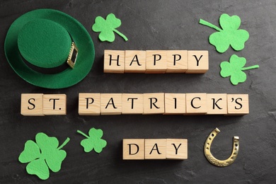 Words Happy St. Patrick's day, hat and festive decor on black slate background, flat lay