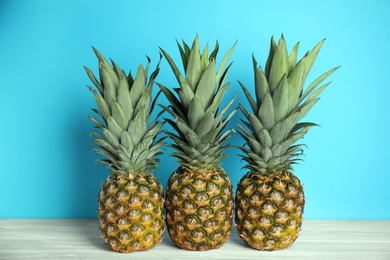 Photo of Fresh ripe juicy pineapples on white wooden table