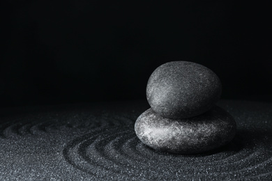 Spa stones on black sand with beautiful pattern, space for text. Zen and harmony