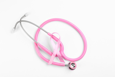 Pink ribbon and stethoscope on white background, top view. Breast cancer awareness