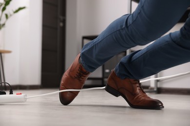 Man tripping over cord in office, closeup