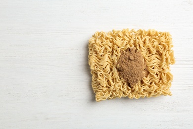 Block of quick cooking noodles with spices on wooden background, top view. Space for text