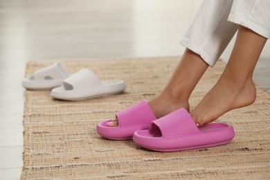 Woman putting on pink slippers indoors, closeup