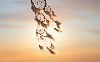 Handmade dream catcher against beautiful sunset sky. Space for text