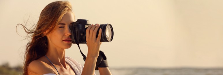 Photographer taking photo with professional camera near sea, space for text. Banner design