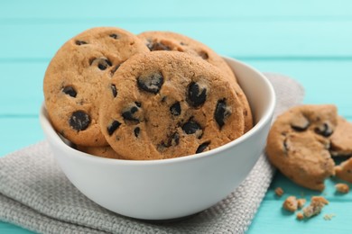 Bowl with many delicious chocolate chip cookies on turquoise table, closeup