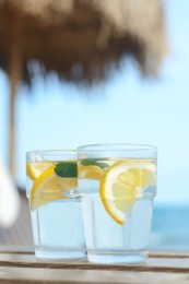 Photo of Refreshing water with lemon and mint on wooden table outdoors