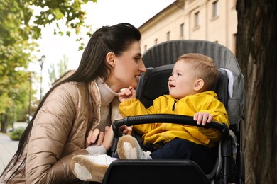 Happy mother with her son in stroller outdoors