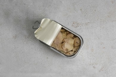 Photo of Open tin can of tasty cod liver on textured table, top view