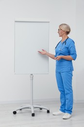 Photo of Professional doctor explaining something near flipchart indoors