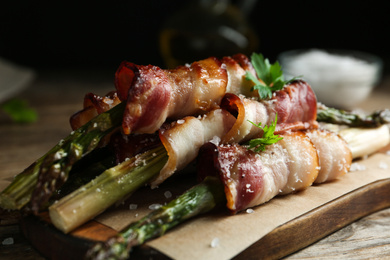 Oven baked asparagus wrapped with bacon on wooden board, closeup