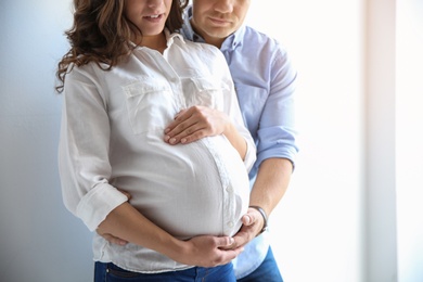 Pregnant woman with her husband on white background. Space for text