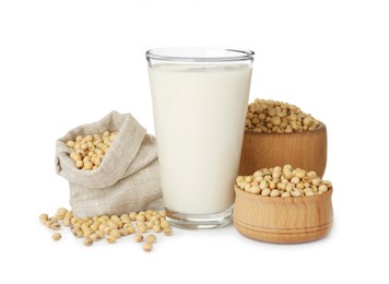 Glass of fresh soy milk and beans on white background