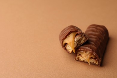 Photo of Pieces of chocolate bar with caramel on beige background. Space for text