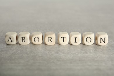 Word Abortion made of wooden cubes on grey table, closeup